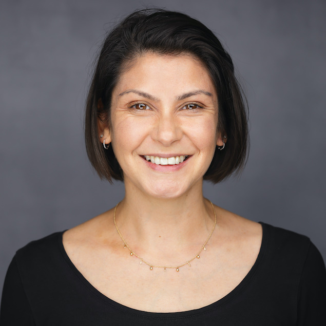 A professional headshot of a light-skinned woman with chin length black hair, smiling.